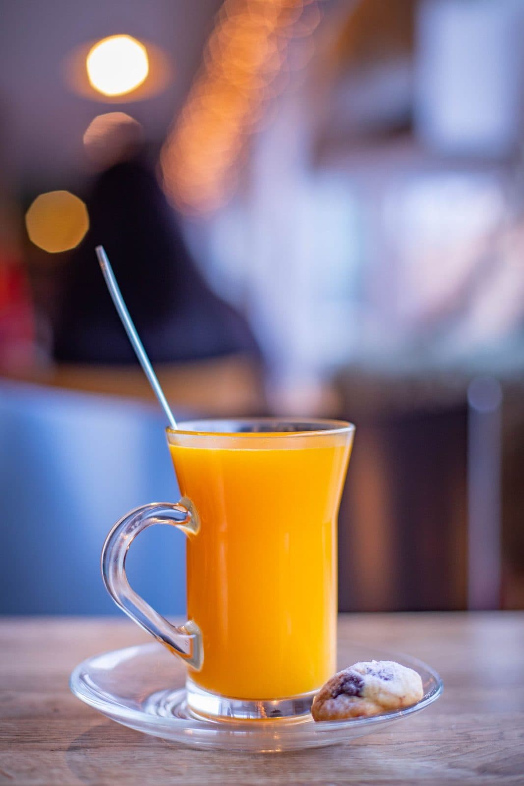 Hot non-alcoholic orange-mango punch in a glass mug with a biscuit